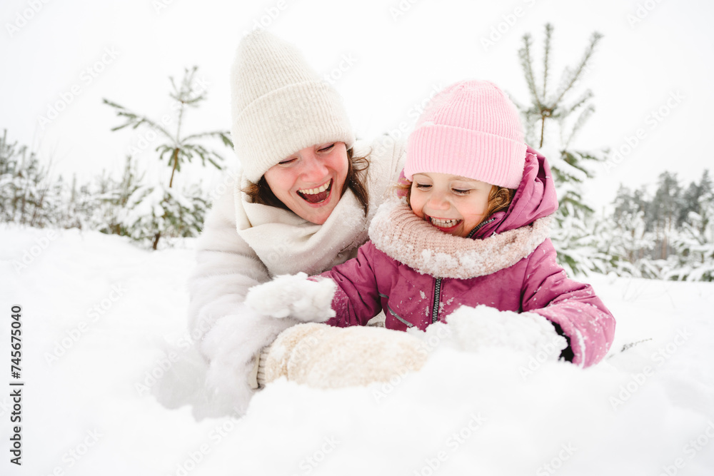 Cheerful mother and daughter having fun in snow at winter park Cheerful mother and daughter having fun in snow at winter park