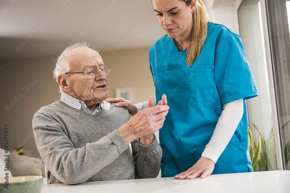 Senior man discussing with home caregiver at table Senior man discussing with home caregiver at table