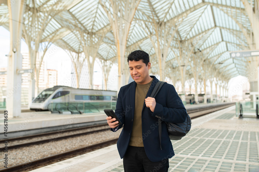 Smiling businessman using smart phone at station platform Smiling businessman using smart phone at station platform