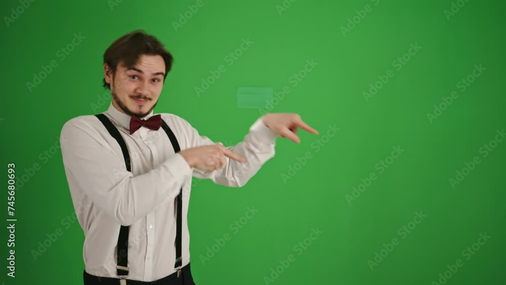 Cheerful Young Man Pointing Left with Both Hands on Green Background Cheerful Young Man Pointing Left with Both Hands on Green Background