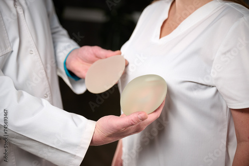 Photography Close-up of female plastic surgeon demonstrates breast implants to a patient for her new breast