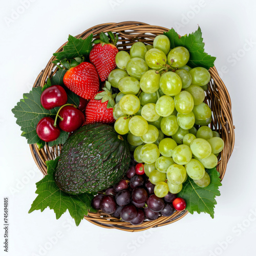 A top view of a wicker basket filled with a colorful variety of fresh fruits including grapes  strawberries  and avocados.