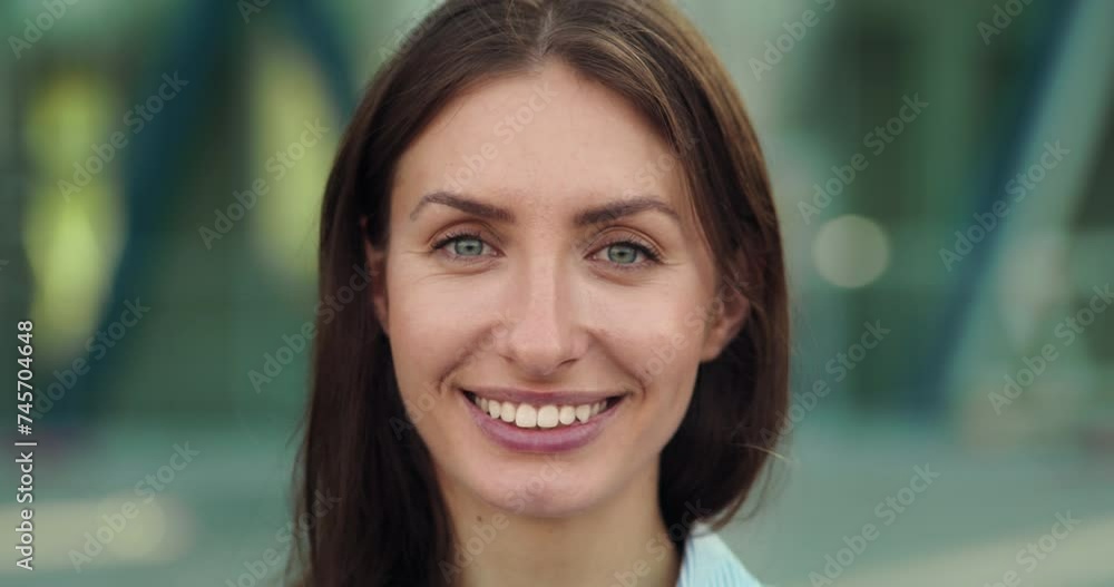 Close up of young confident successful formally dressed business woman is smiling in camera outside her office before to start working day. Close up of young confident successful formally dressed business woman is smiling in camera outside her office before to start working day.
