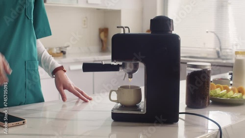 Cropped shot of healthcare worker in uniform making coffee at kitchen while preparing for work photo