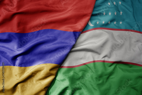big waving national colorful flag of uzbekistan and national flag of armenia .