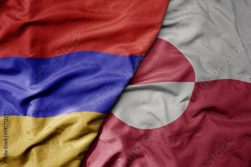 big waving national colorful flag of greenland and national flag of armenia .