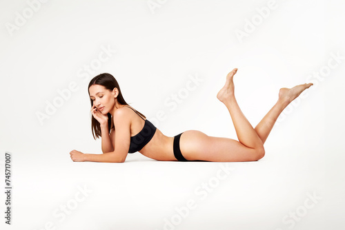 Perfect young woman with sporty body in black underwear lying on floor