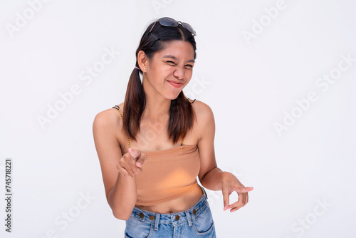 фотографія A young Filipino woman winks and points playfully, teasing someone in a casual setting with joy