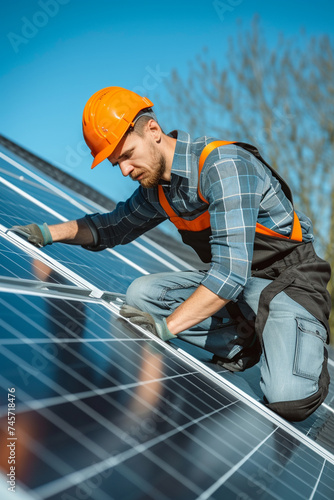 a male craftsman installs solar panels on the roof of a house