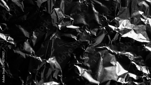 Crumpled foil with glimpses of light and moving shadow along the wrinkles close up photo