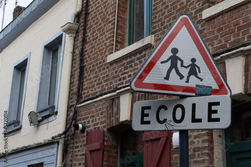Segnale stradale triangolare di pericolo per attraversamento bambini e genitori vicino a una scuola, con la scritta ECOLE che significa SCUOLA
