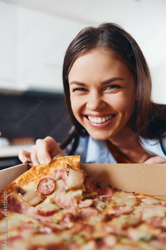 Happy woman holding up a delicious pizza with ham and cheese in a box, smiling with joy Happy woman holding up a delicious pizza with ham and cheese in a box, smiling with joy