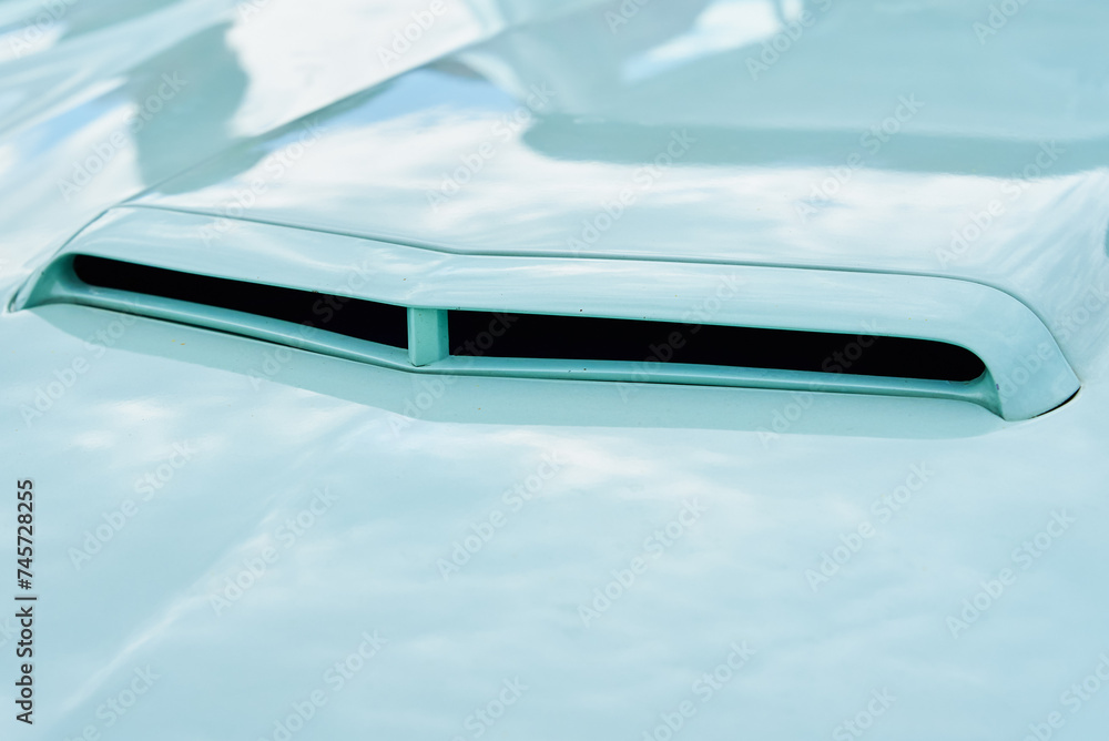 Close-up view of air intake vent on hood of retro sports car, reflecting the bright daylight Close-up view of air intake vent on hood of retro sports car, reflecting the bright daylight