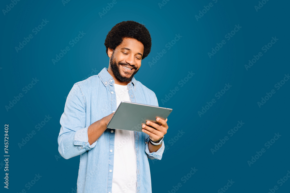 Engaged and content Brazilian young man, freelancer or student using a tablet, managing tasks or catching up on news, demonstrating the integral role of tablets in staying informed and organized Engaged and content Brazilian young man, freelancer or student using a tablet, managing tasks or catching up on news, demonstrating the integral role of tablets in staying informed and organized