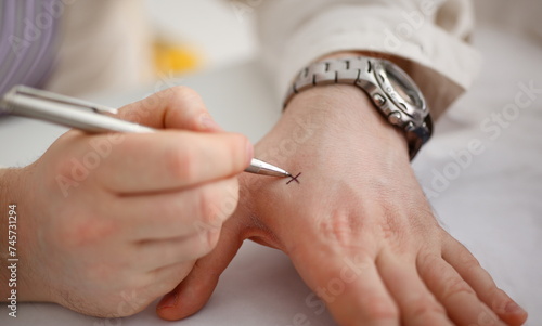 Male make x cross note with silver pen at his arm