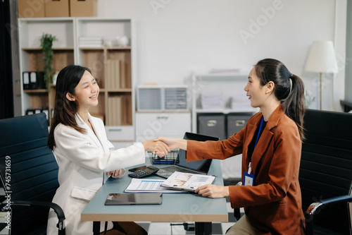 Businesswomen work and discuss their business plans. A Human employee explains and shows her colleague the results paper