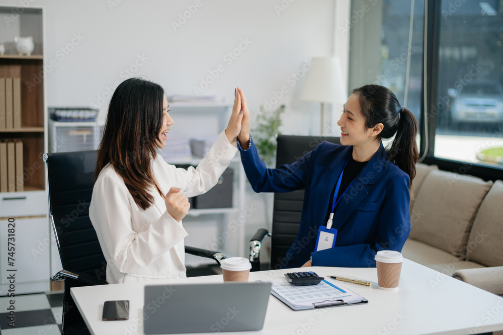 Female discussing new project with Female colleague. Young women talking with young Asian man in office. Female discussing new project with Female colleague. Young women talking with young Asian man in office.