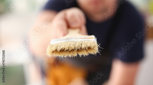 Arm of smiling worker hold brush closeup