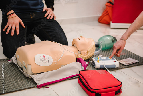 Use an automatic defibrillator in conducting basic cardiopulmonary resuscitation of victim. Automated external defibrillator device, AED with training dummy mannequin. Demonstrating chest compressions