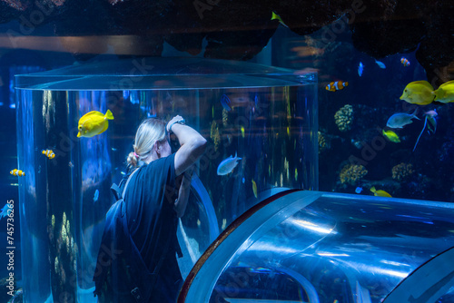 girl taking pictures of fish in an aquarium