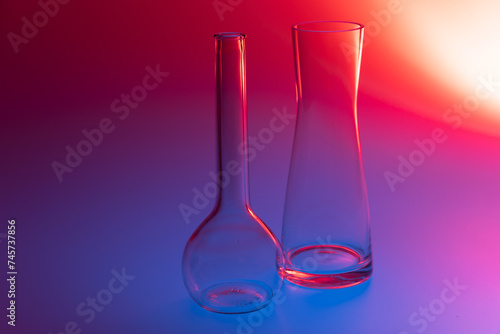 Close-up of two decorative glass vases on a red, blue and violet colored background