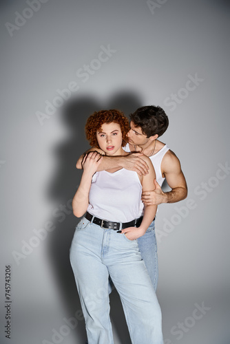 attractive man in jeans hugging his beautiful girlfriend while she looking at camera, sexy couple