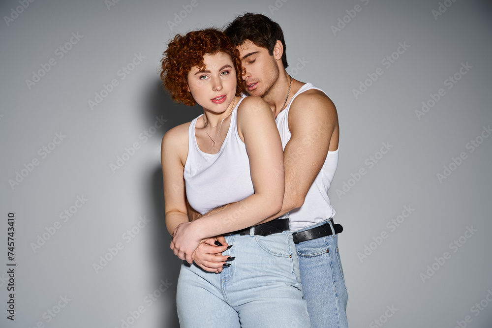 handsome man in jeans hugging his beautiful girlfriend while she looking at camera, sexy couple handsome man in jeans hugging his beautiful girlfriend while she looking at camera, sexy couple