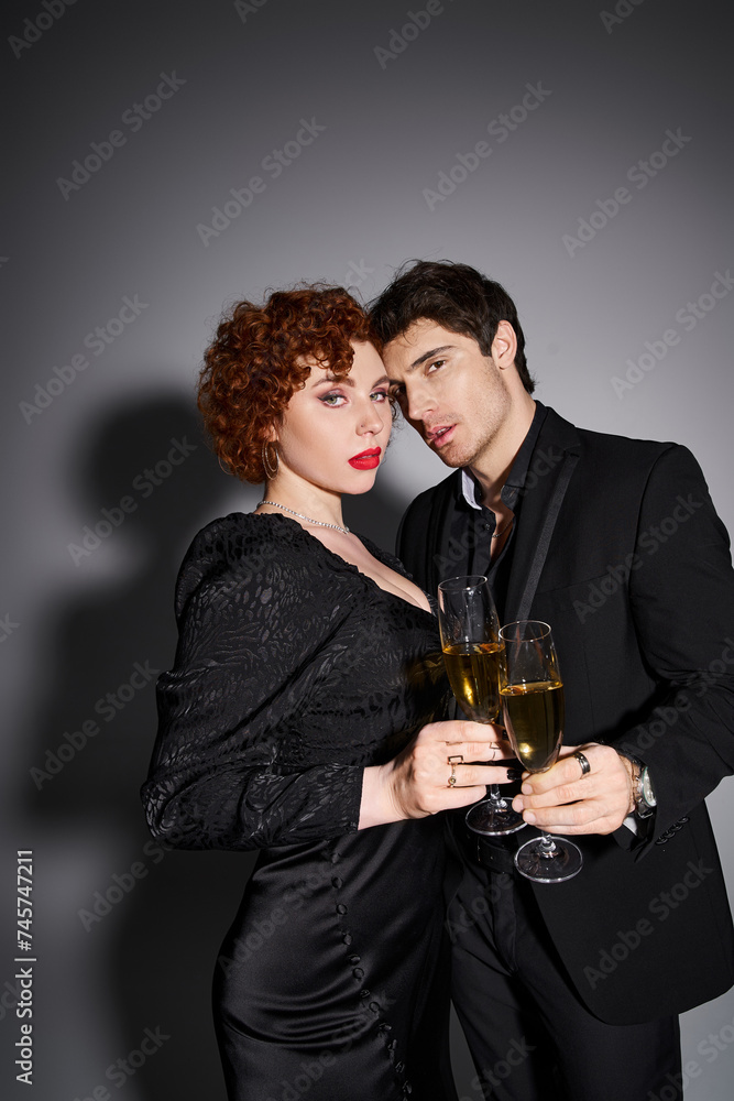 sexy good looking couple in black attire hugging and looking at camera with champagne in hands sexy good looking couple in black attire hugging and looking at camera with champagne in hands