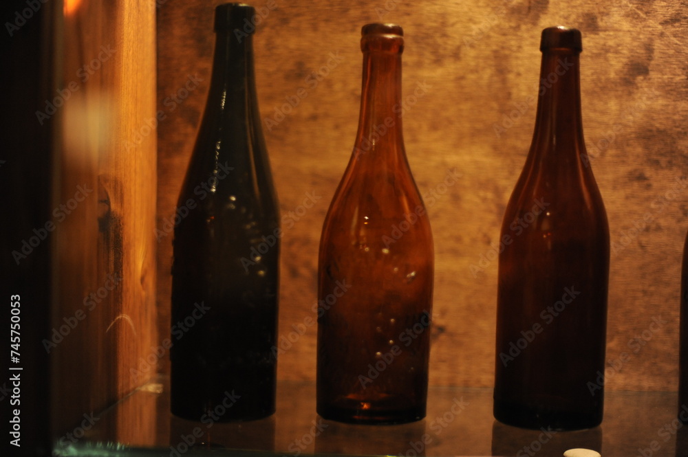 Empty antique brown beer bottles standing in a row on a shelf in a cellar Empty antique brown beer bottles standing in a row on a shelf in a cellar