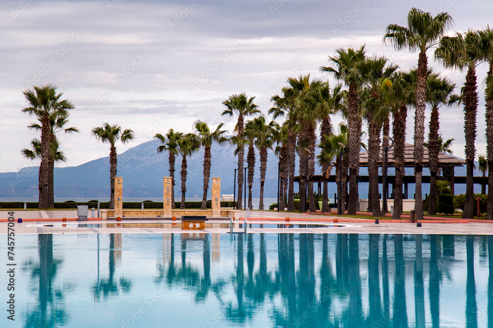 Swimming pool with palm trees in Aegean sea, Turkey. Tropical resort 