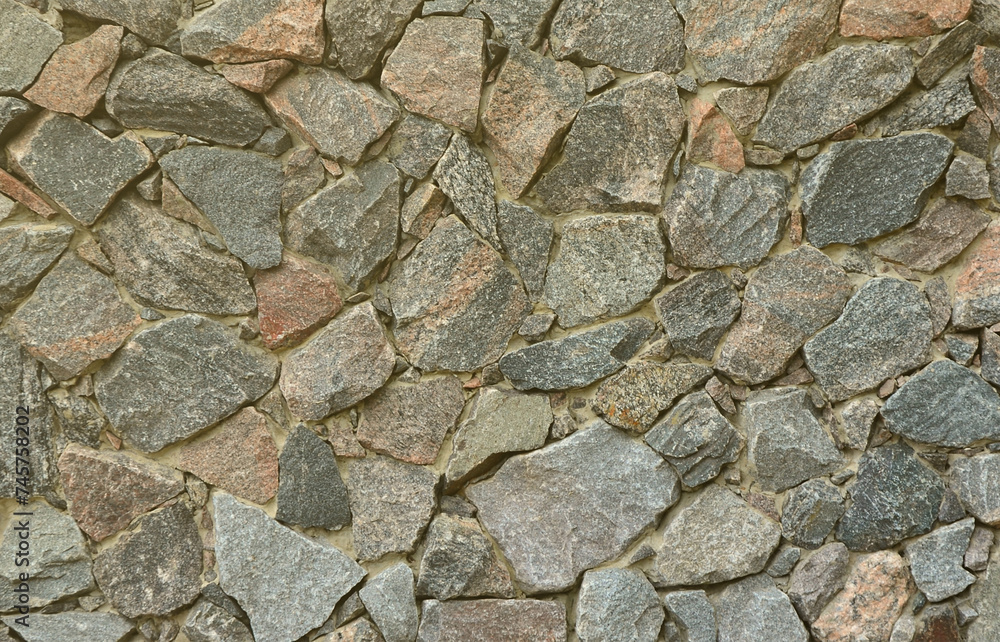 The texture of a strong stone wall of many concreted stones of various shapes