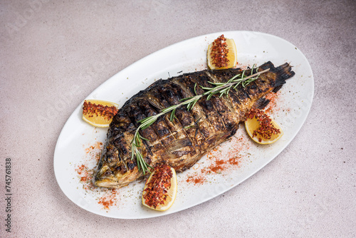 Delicious grilled fish with lemon and rosemary on a white plate