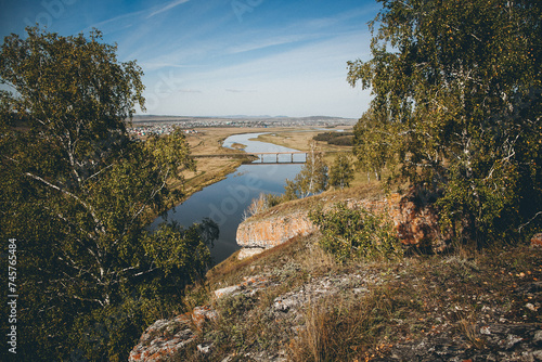 River flowing in valley with trees and rocks, under open sky