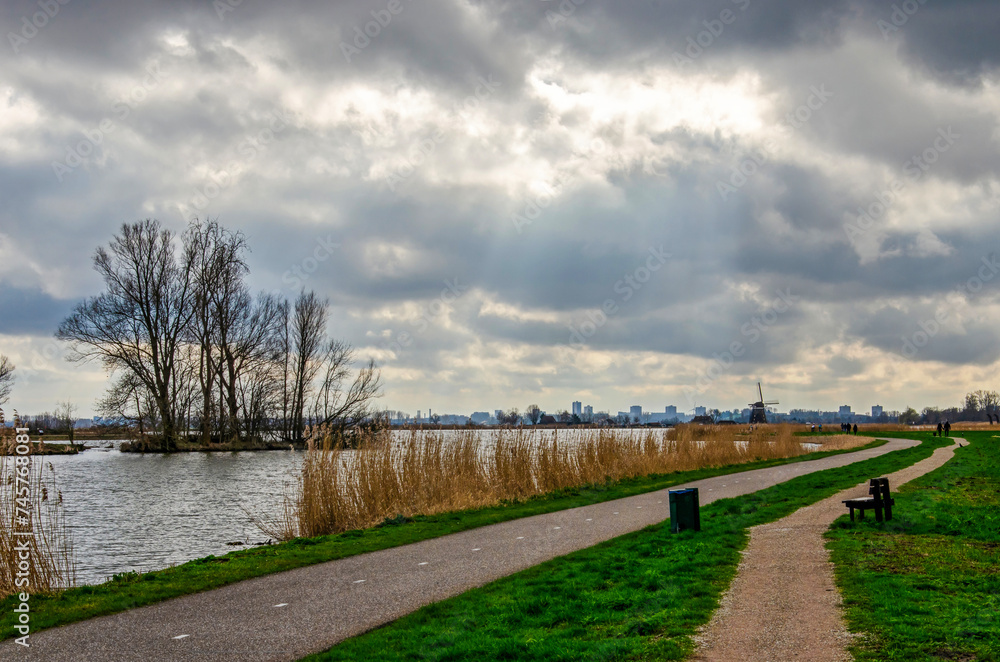 A footpath and a bicycle path along the river Rotte in the Netherlands under a dramatic sky