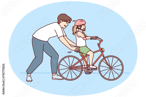 Loving father helps pre-teenage daughter learn to ride bike. Happy childhood for little girl in helmet learning to ride bicycle under supervision of caring dad or brother
