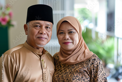 Portrait of a Malay Muslim couple welcoming their guest for the celebration of Hari Raya 