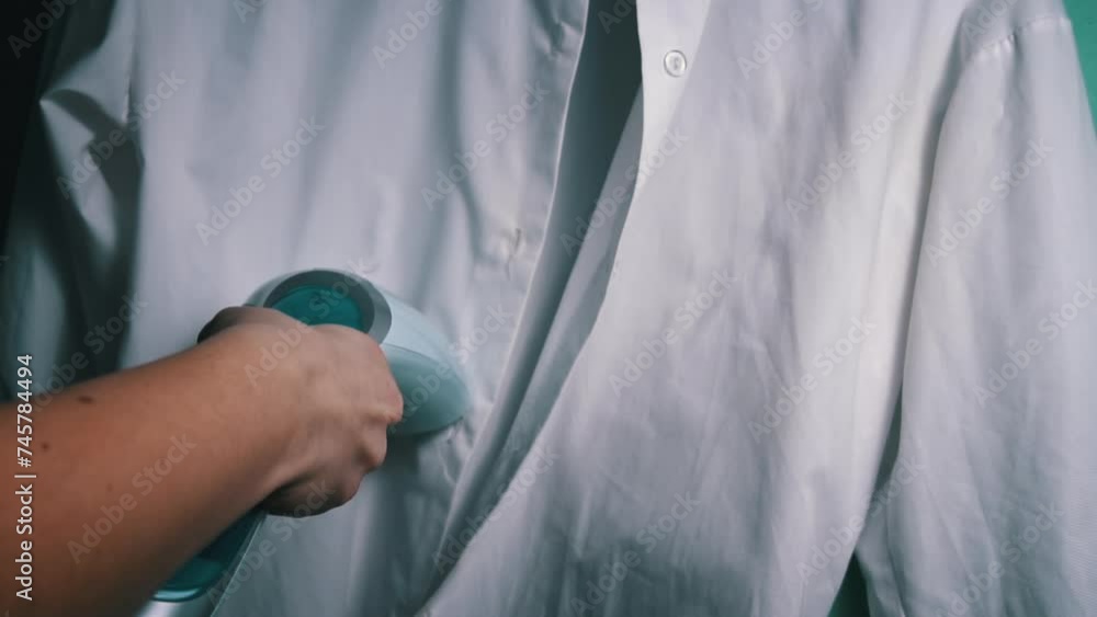 Handheld Steam Iron Smoothing White Shirt depicts a steam iron in