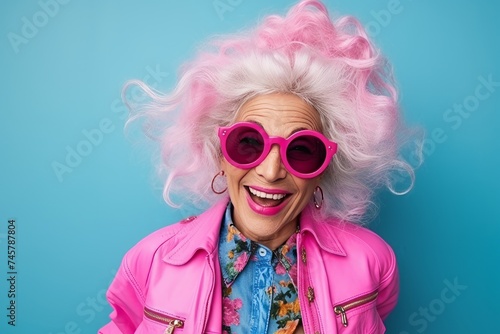 Funny senior woman with pink hair and sunglasses on a blue background