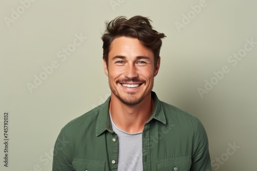 Portrait of a handsome young man smiling against a green background.