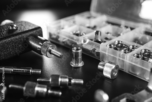 Threaded Insert Riveter Gun Kit. setting tool, nosepieces and inserts, for all types of rivets, including threaded rivet nuts, pliers. black background, selective focus. Black and white photo
