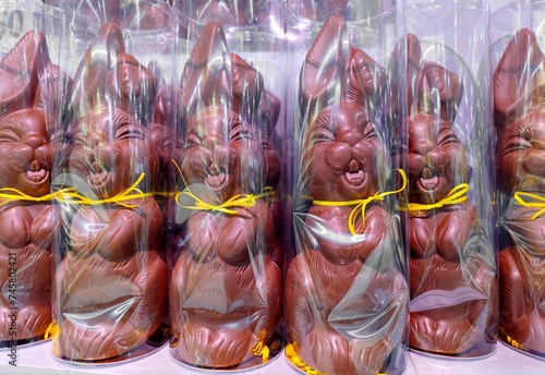 Giant chocolate Easter bunnies with yellow ribbon bow tie in plastic packaging are on supermarket shelves and are ready to be sold for Easter