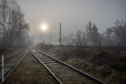 Morning misty landscape with railway tracks and sun