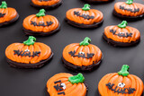 Halloween cookies. on a matte black table lies a large number of creative bright cookies in the shape of pumpkins, sweet concept