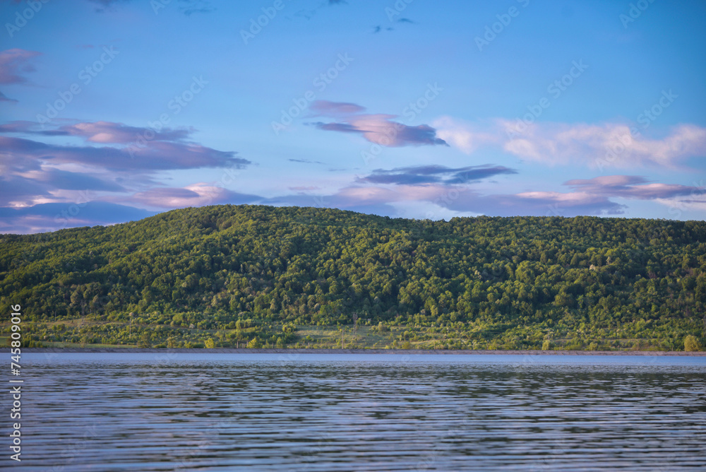 A large lake with calm waters at the edge of a picturesque tall forest in a village far from the cities
