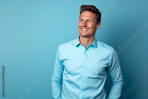 Portrait of a handsome smiling young man in blue shirt on blue background