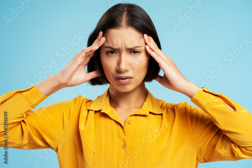 Sad asian woman looking at camera, standing isolated on blue background. Health care concept