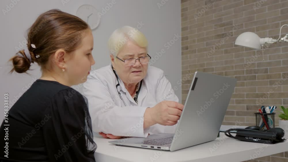 Woman doctor showing results to girl on laptop screen. Concept of medical, healthcare, healthy family, pediatric checkup and hospital office.