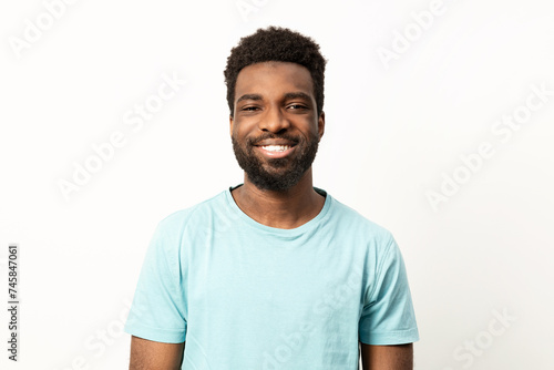 Portrait of a happy young African American man with a bright smile, posing against a clean, plain background in a casual t-shirt.