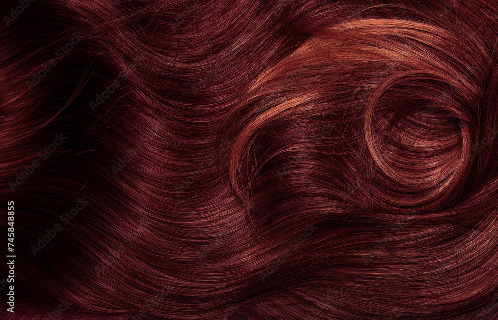 Naklejka premium Dark red hair close-up as a background. Women's long brown hair. Beautifully styled wavy shiny curls. Coloring hair with bright shades. Hairdressing procedures, extension.