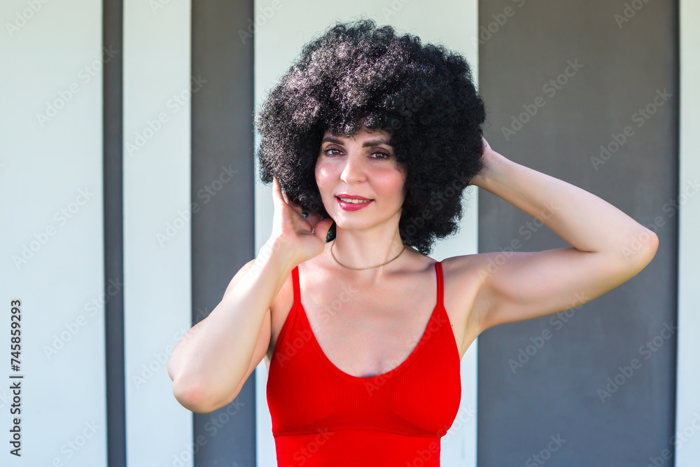 Portrait of a woman with black lush hair near a striped wall. Portrait of a woman with black lush hair near a striped wall.
